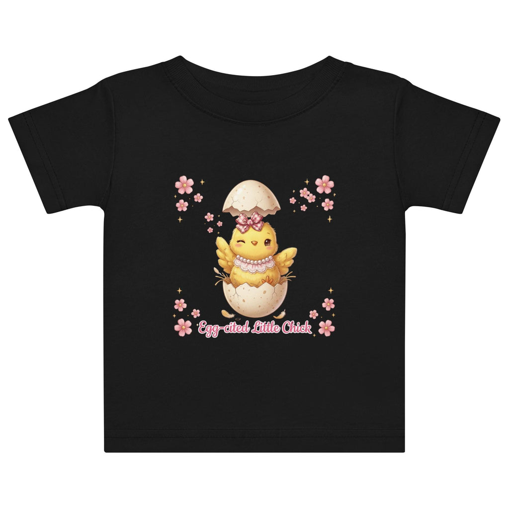 May include: White short-sleeved t-shirt featuring a cartoon chick hatching from an egg, with the text "Egg-cited Little Chick" in pink. The chick is yellow with a pink bow and necklace. The child is wearing a pink bow.