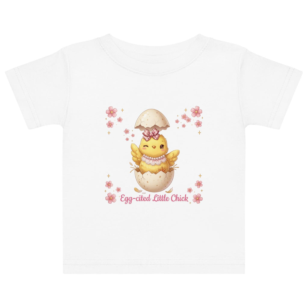 May include: White short-sleeved t-shirt featuring a cartoon chick hatching from an egg, with the text "Egg-cited Little Chick" in pink. The chick is yellow with a pink bow and necklace. The child is wearing a pink bow.