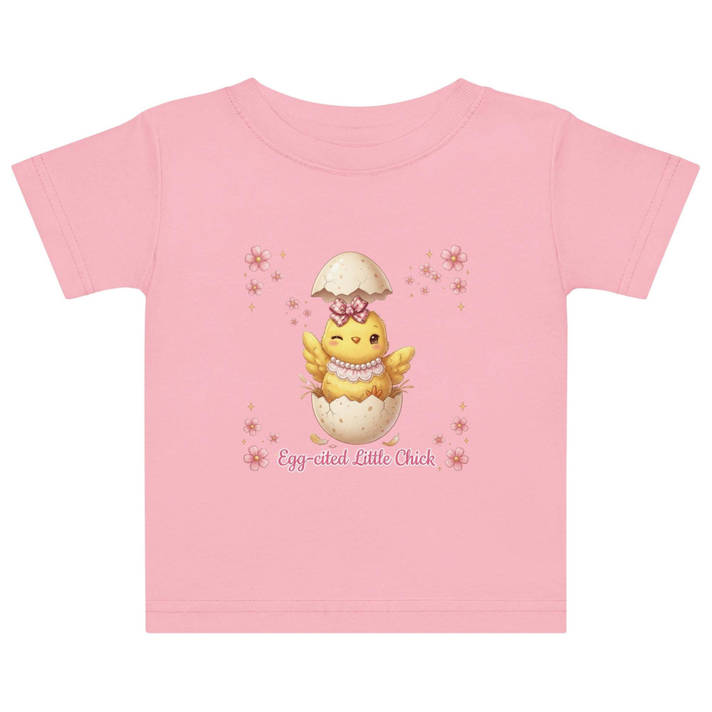 May include: White short-sleeved t-shirt featuring a cartoon chick hatching from an egg, with the text "Egg-cited Little Chick" in pink. The chick is yellow with a pink bow and necklace. The child is wearing a pink bow.