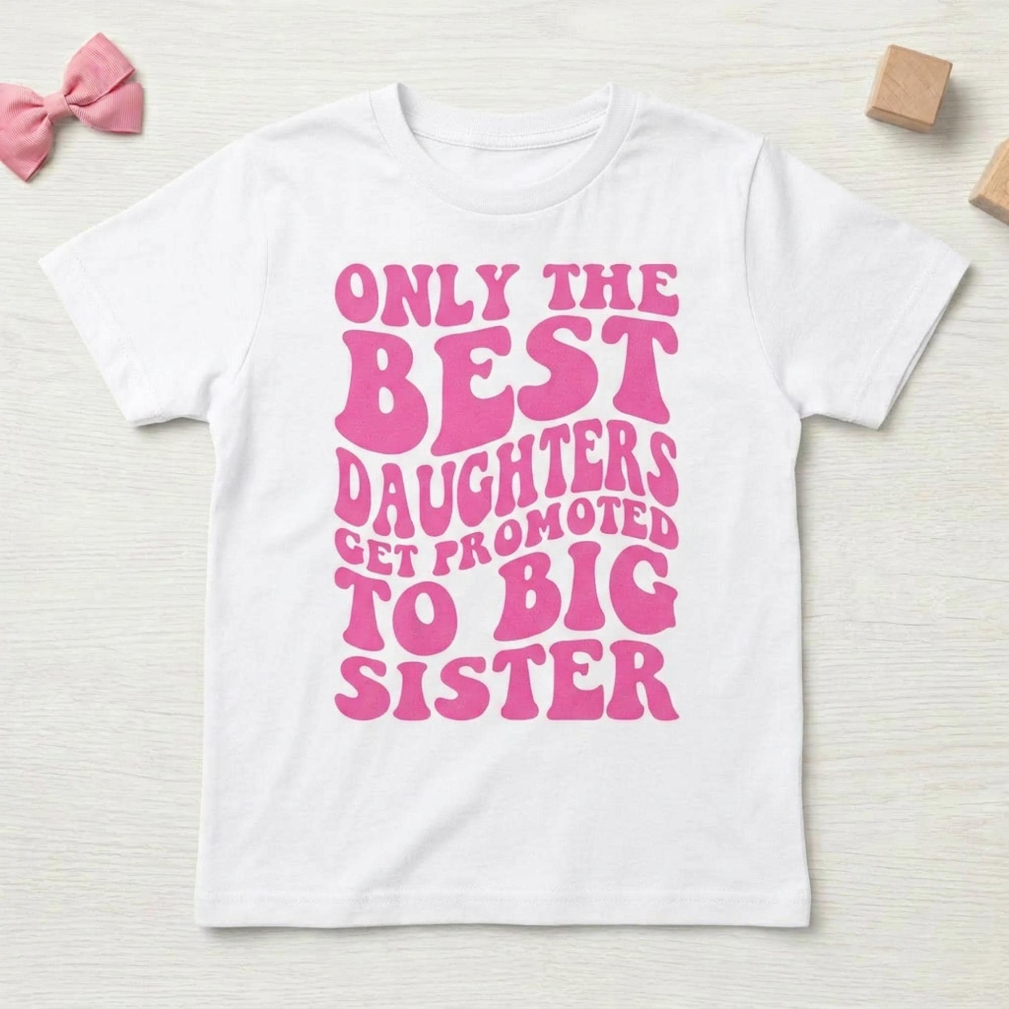 May include: White t-shirt with the text "ONLY THE BEST DAUGHTERS GET PROMOTED TO BIG SISTER" in pink, retro-style lettering. The shirt is a short-sleeved crew neck.