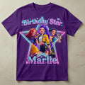 May include: Purple t-shirt featuring a graphic of three cartoon singers inside a star-shaped frame. The text "Birthday Star" and "Marlie" are displayed in a neon-style font. The singers are holding microphones.